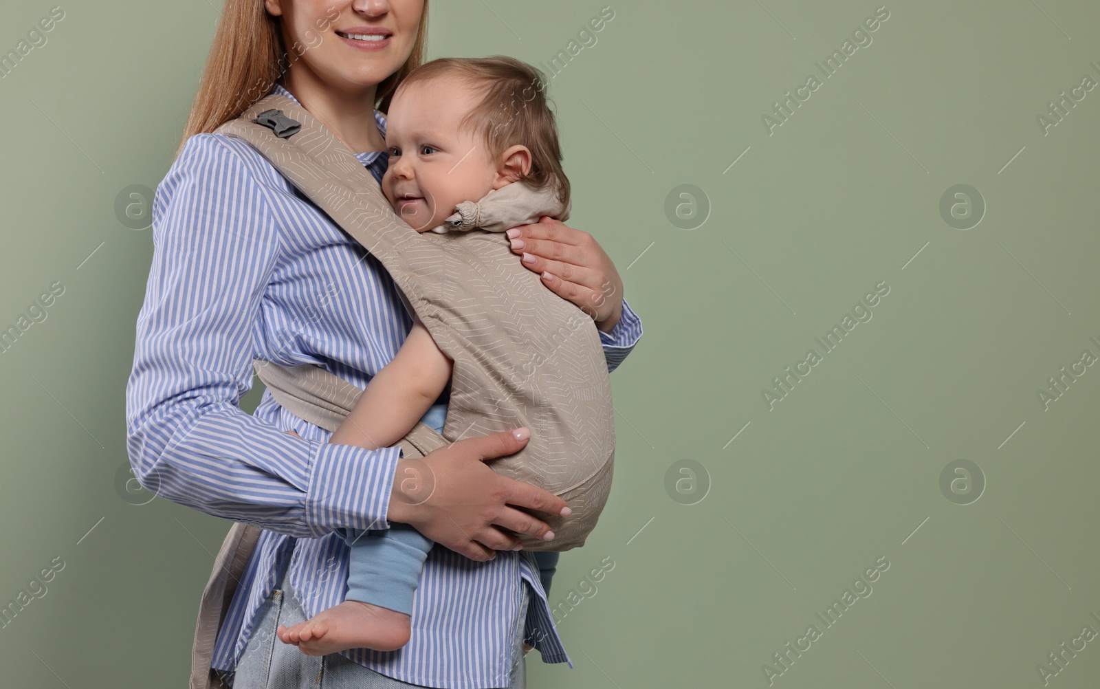 Photo of Mother holding her child in sling (baby carrier) on olive background, closeup. Space for text