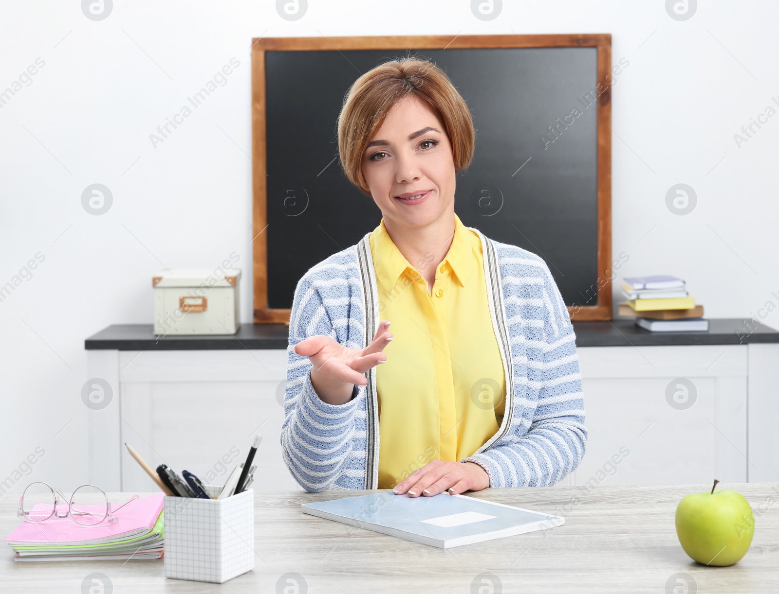 Photo of Portrait of female teacher sitting at table in classroom