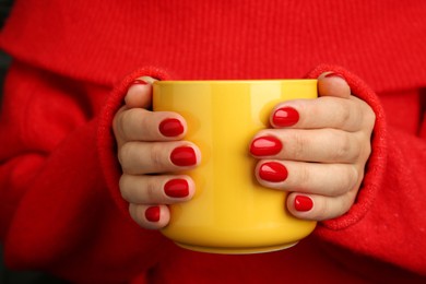 Photo of Woman with red polish on nails holding cup, closeup