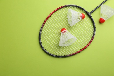 Photo of Badminton racket and shuttlecocks on light green background, flat lay. Space for text