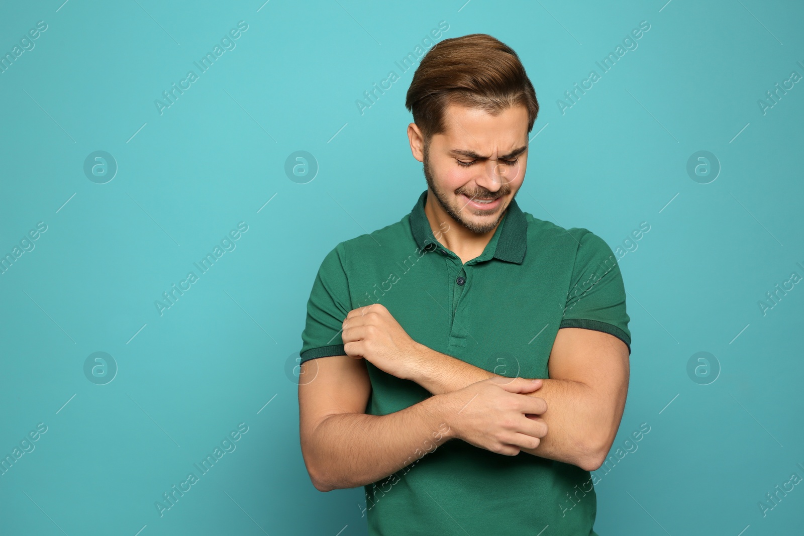 Photo of Young man scratching arm on color background, space for text. Annoying itch