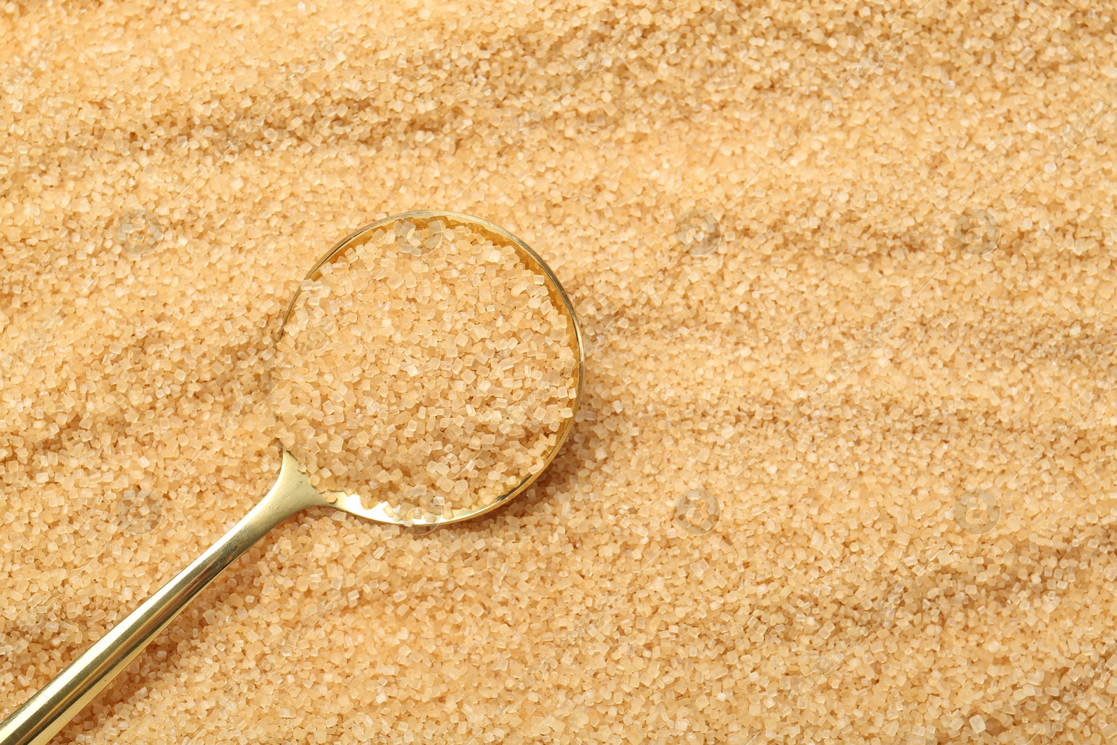 Photo of Spoon on granulated brown sugar, top view