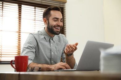 Photo of Man using video chat on laptop in home office