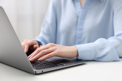 E-learning. Woman using laptop at white table indoors, closeup