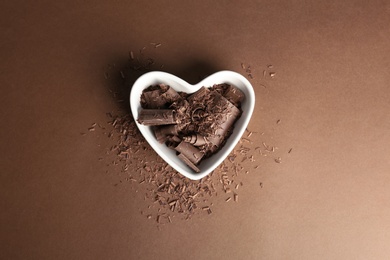 Bowl with chocolate curls on color background, top view