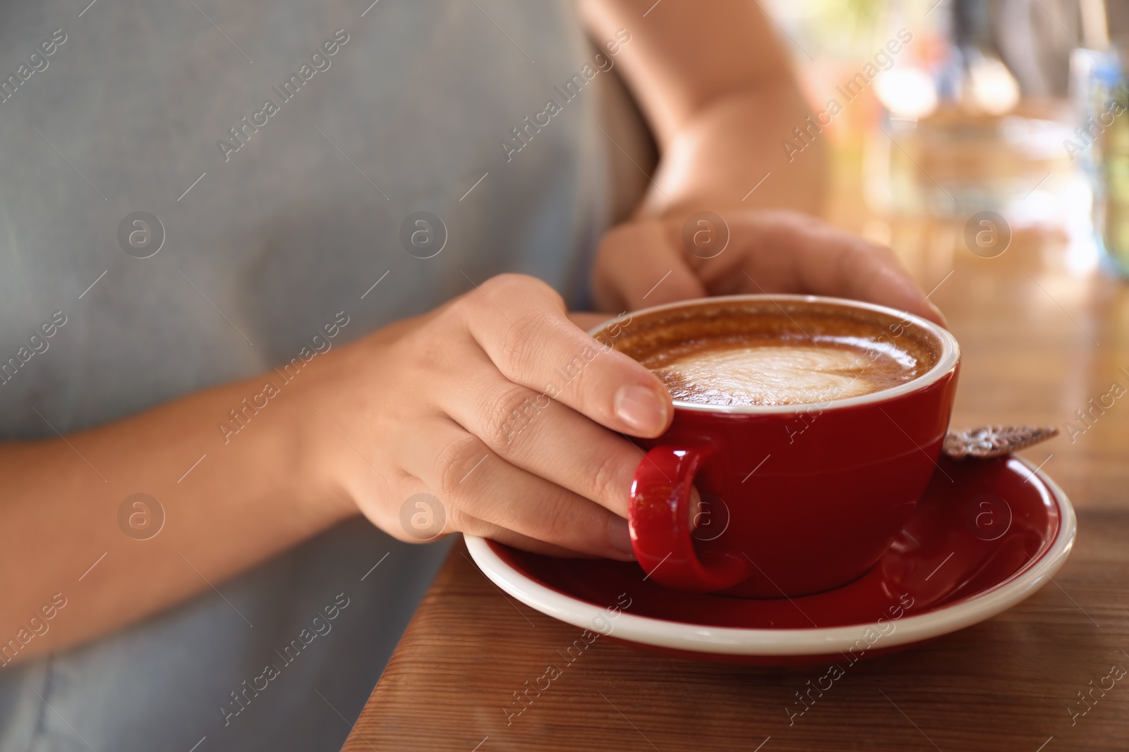 Photo of Woman with cup of fresh aromatic coffee at table, closeup