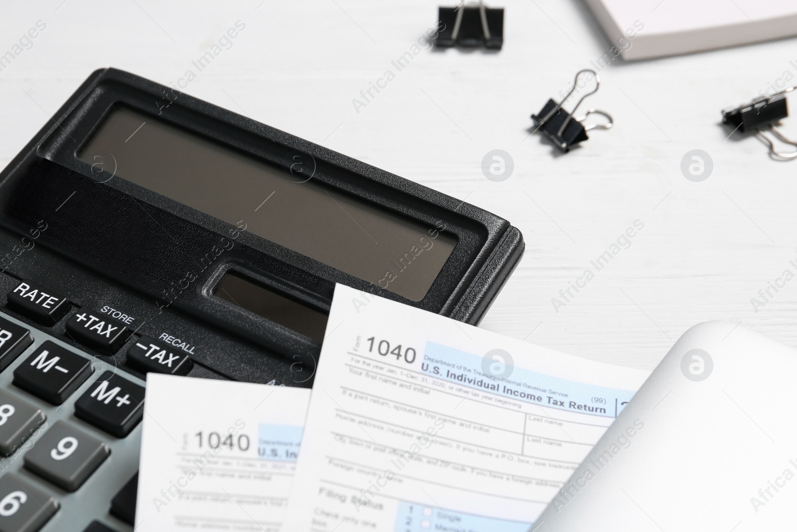 Photo of Calculator, documents and clips on white wooden table, closeup. Tax accounting