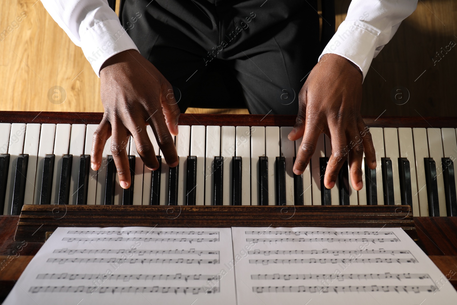 Photo of African-American man playing piano indoors, above view. Talented musician