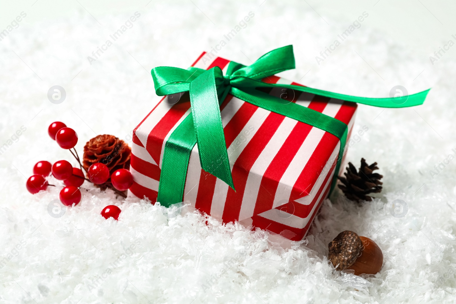 Photo of Christmas gift box with green bow and festive decor on snow