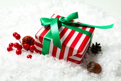 Christmas gift box with green bow and festive decor on snow