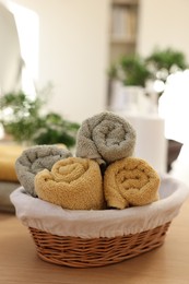 Photo of Basket with towels on wooden table indoors. Spa time