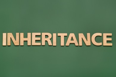 Word Inheritance made with wooden letters on green background, flat lay