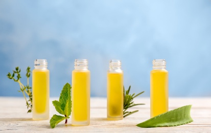 Bottles with essential oils and fresh herbs on table