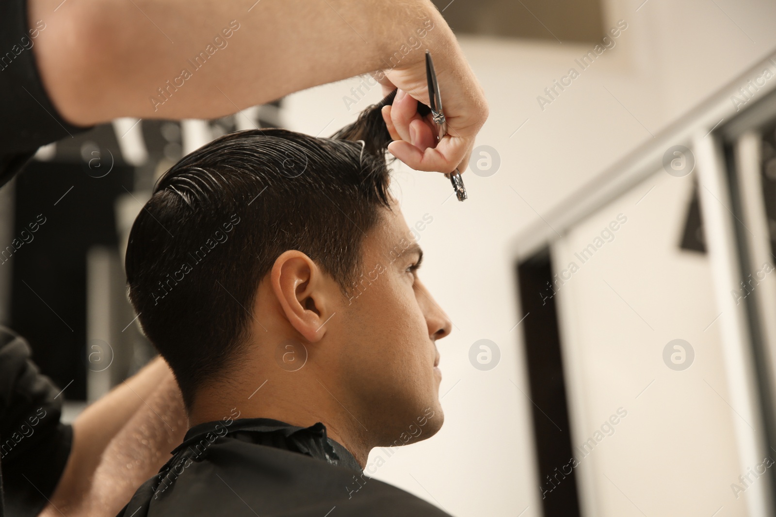 Photo of Professional barber making stylish haircut in salon, closeup. Space for text
