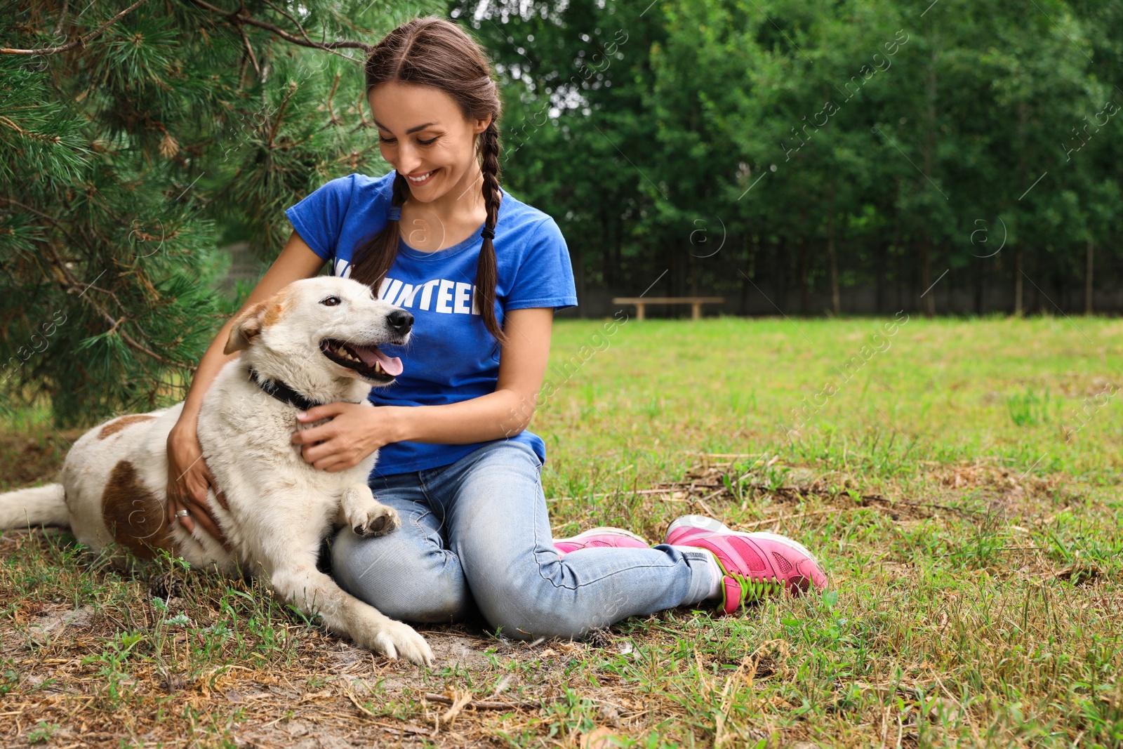 Photo of Female volunteer with homeless dog at animal shelter outdoors