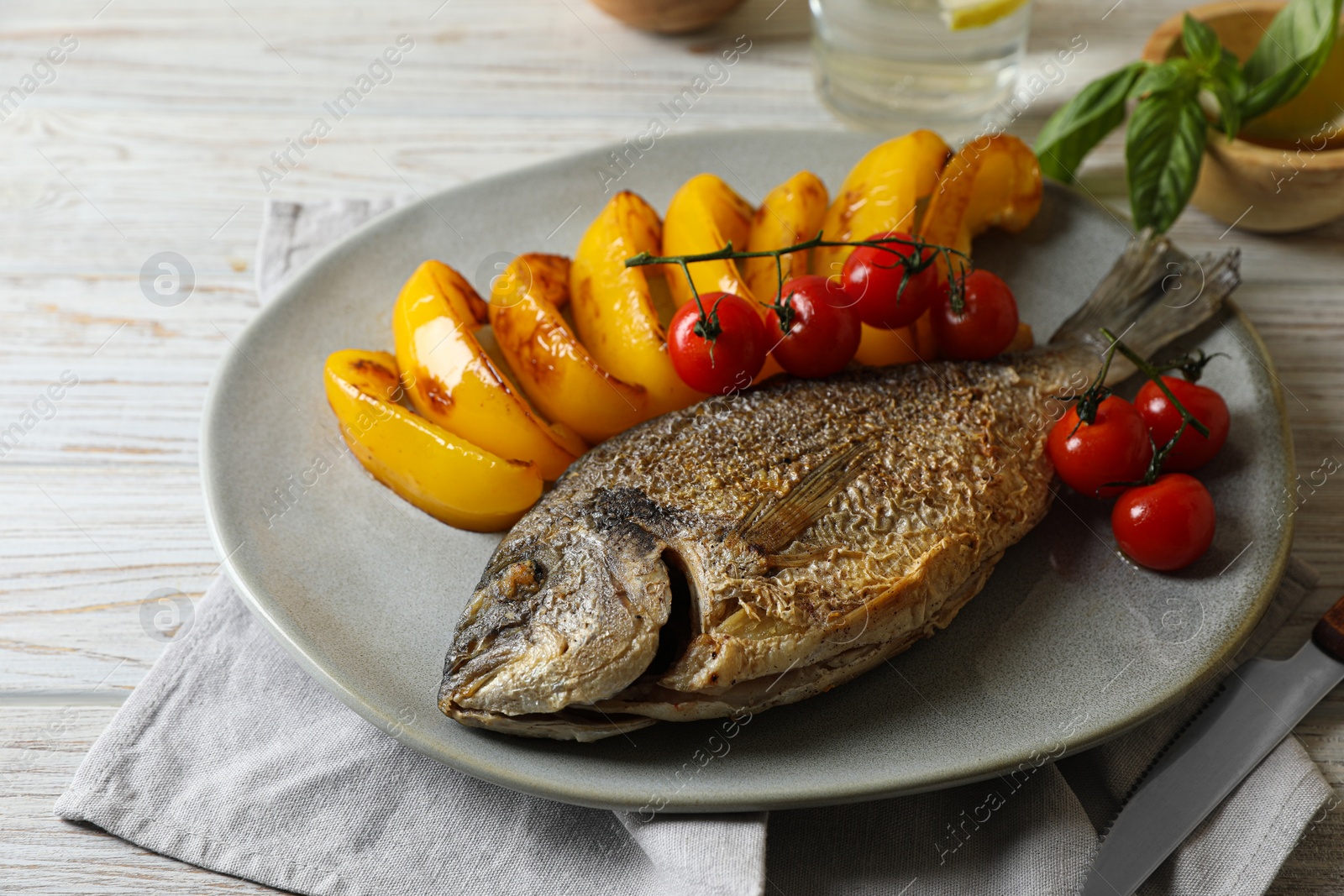 Photo of Delicious roasted dorado fish, bell pepper and tomatoes on wooden table, closeup