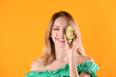 Portrait of young beautiful woman with ripe delicious avocado on color background