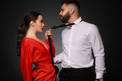 Photo of Handsome bearded man with sexy lady on dark background