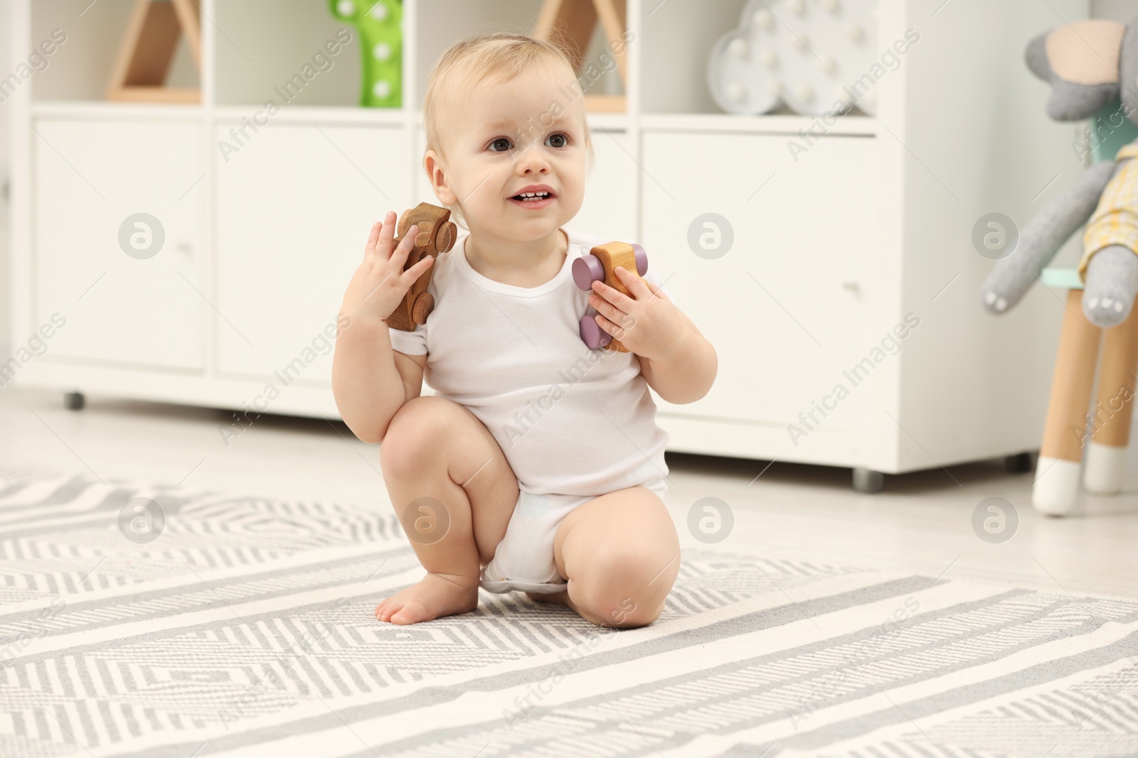 Photo of Children toys. Cute little boy playing with wooden cars on rug at home