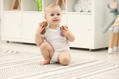 Children toys. Cute little boy playing with wooden cars on rug at home