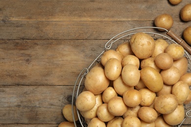 Photo of Raw fresh organic potatoes on wooden background, top view. Space for text