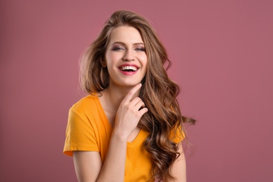 Portrait of young woman with long beautiful hair on color background