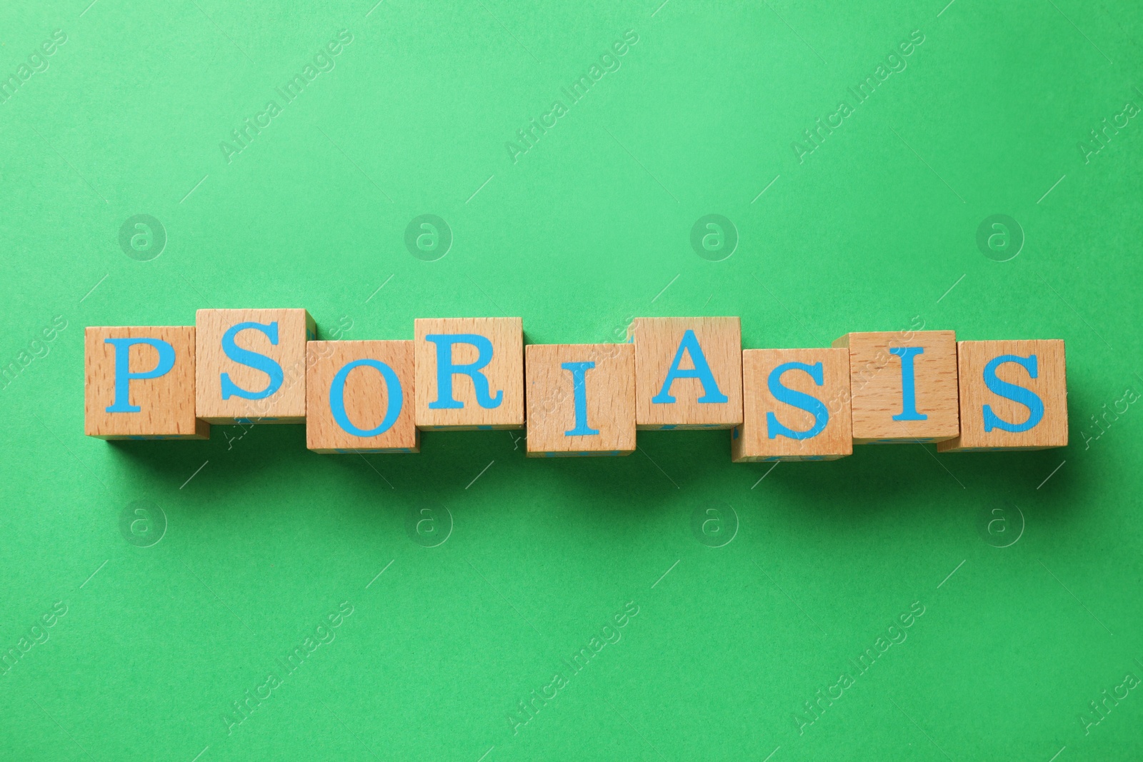 Photo of Word Psoriasis made of wooden cubes with letters on green background, top view