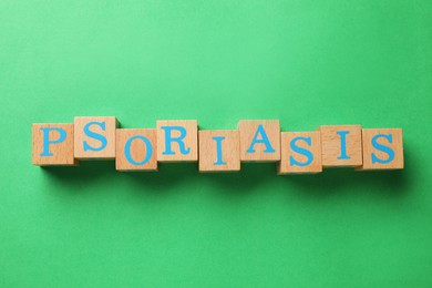 Word Psoriasis made of wooden cubes with letters on green background, top view