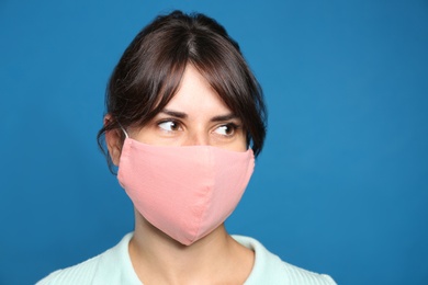 Young woman in protective face mask on blue background