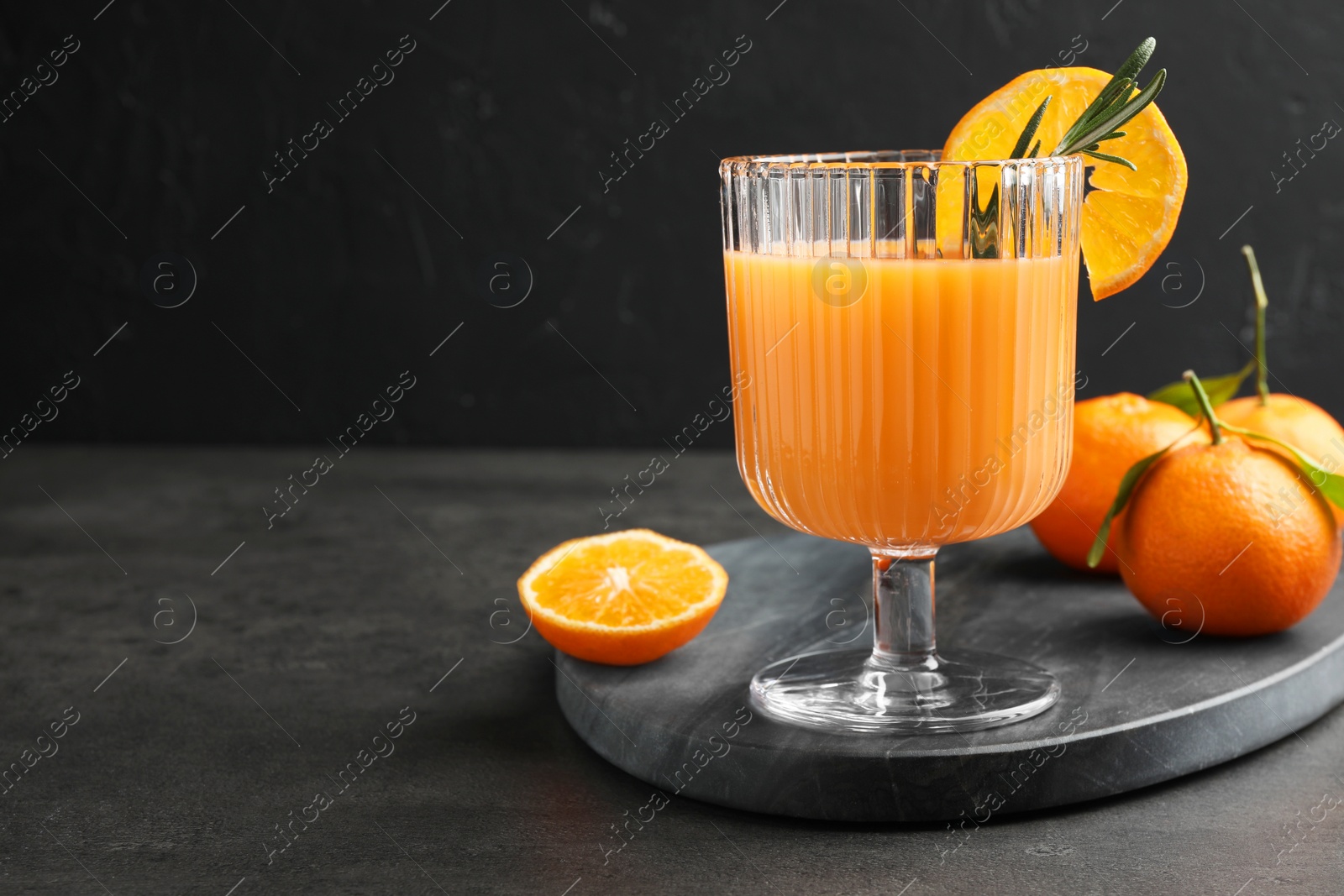 Photo of Delicious tangerine liqueur in glass and fresh fruits on grey table, space for text