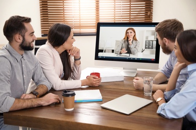 Image of Team of coworkers having video chat with boss in office