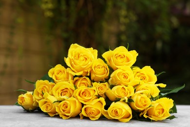 Beautiful bouquet of yellow roses on light table outdoors