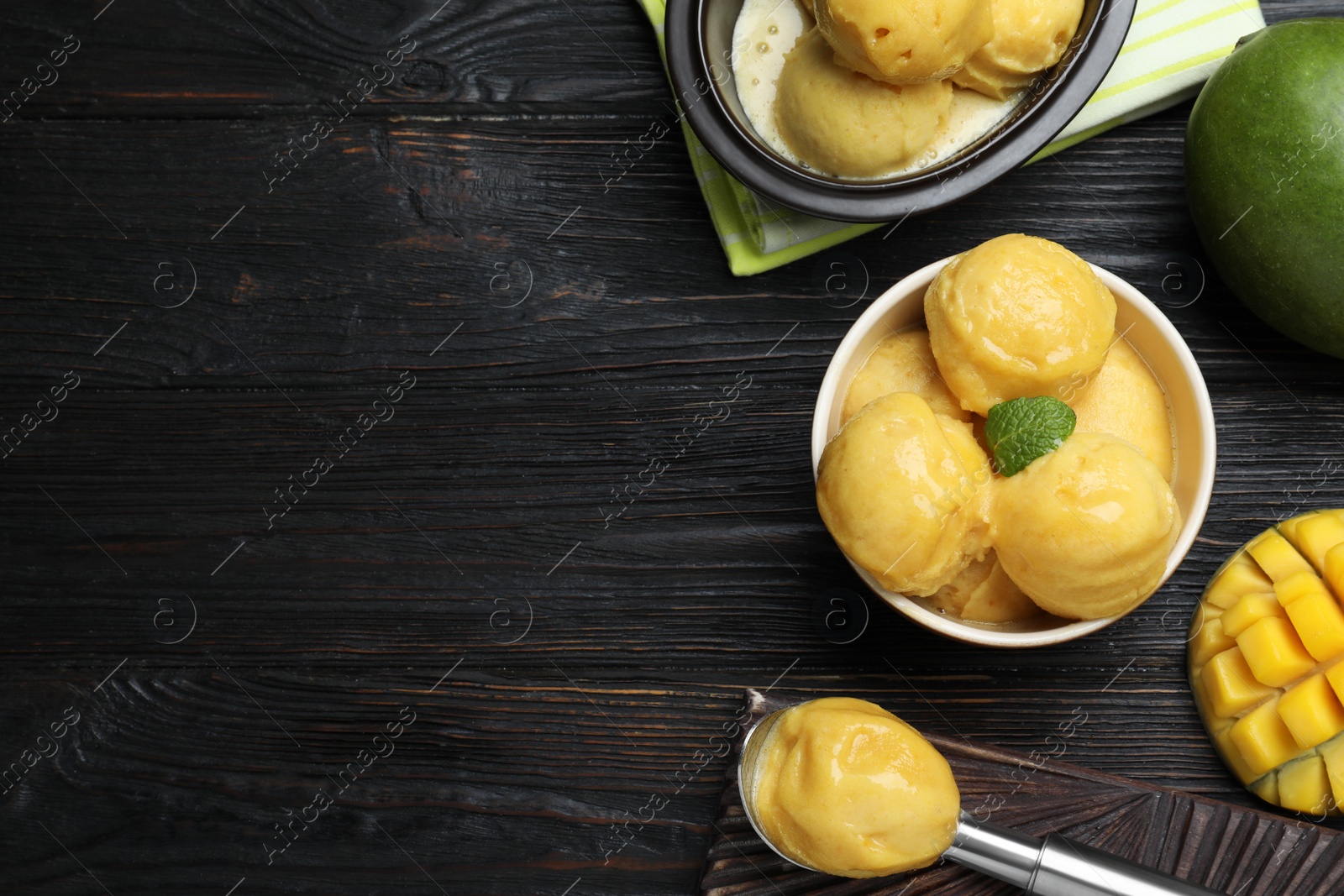 Photo of Yummy mango ice cream served on black wooden table, flat lay. Space for text