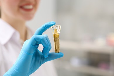 Photo of Dentist holding educational model of dental implant indoors, closeup. Space for text