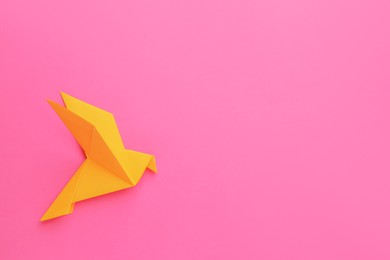 Beautiful orange origami bird on pink background, top view. Space for text