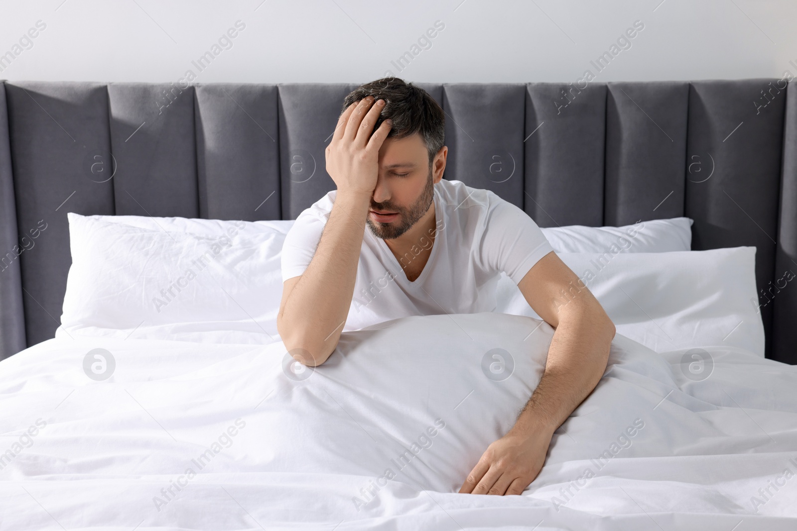 Photo of Sleepy man with blanket on soft bed at home in morning