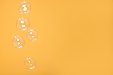 Many beautiful soap bubbles on orange background. Space for text