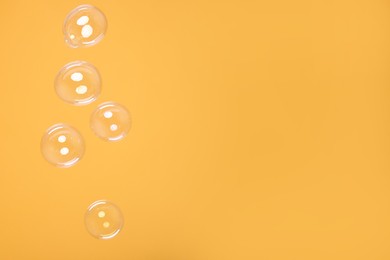 Photo of Many beautiful soap bubbles on orange background. Space for text