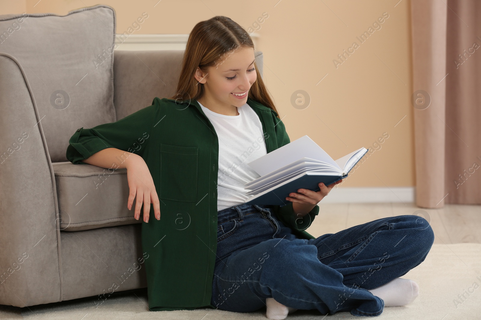 Photo of Teenage girl reading book on floor in room