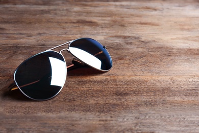 Stylish sunglasses on wooden background, space for text. Fashionable accessory