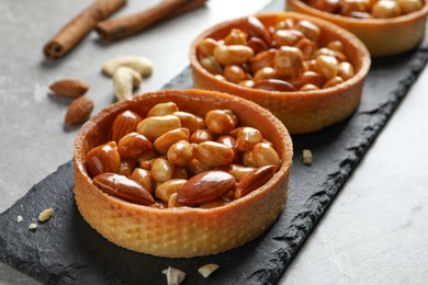 Tartlets with caramelized nuts on light grey table, closeup. Tasty dessert
