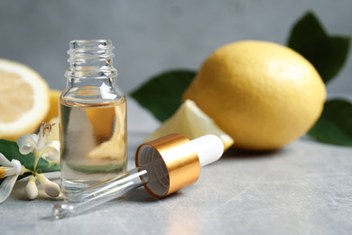 Photo of Citrus essential oil, flower and lemons on light table. Space for text
