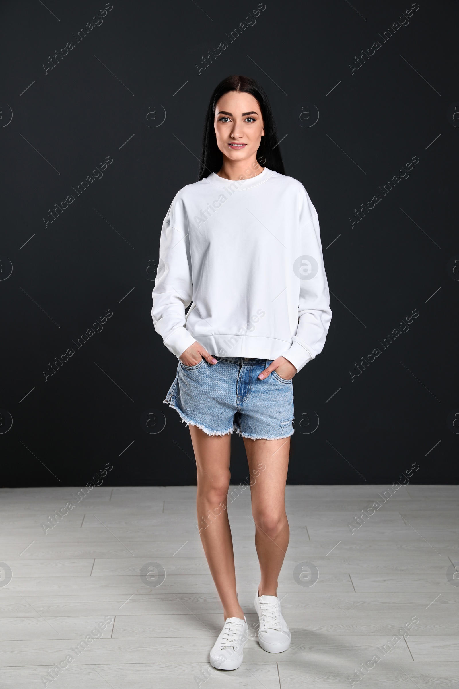 Photo of Full length portrait of young woman in sweater at black wall. Mock up for design