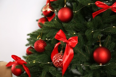Photo of Decorated Christmas tree on light background, closeup