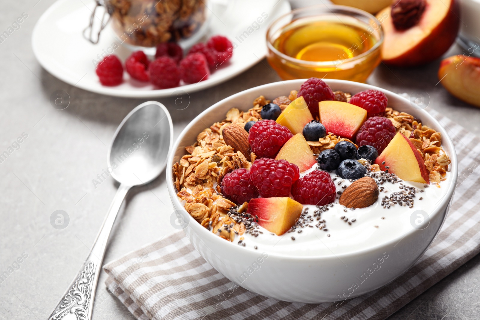Photo of Tasty homemade granola with yogurt served on grey table. Healthy breakfast