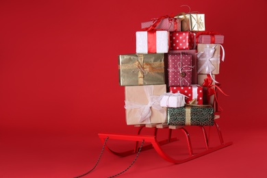 Sleigh with gift boxes on red background. Space for text