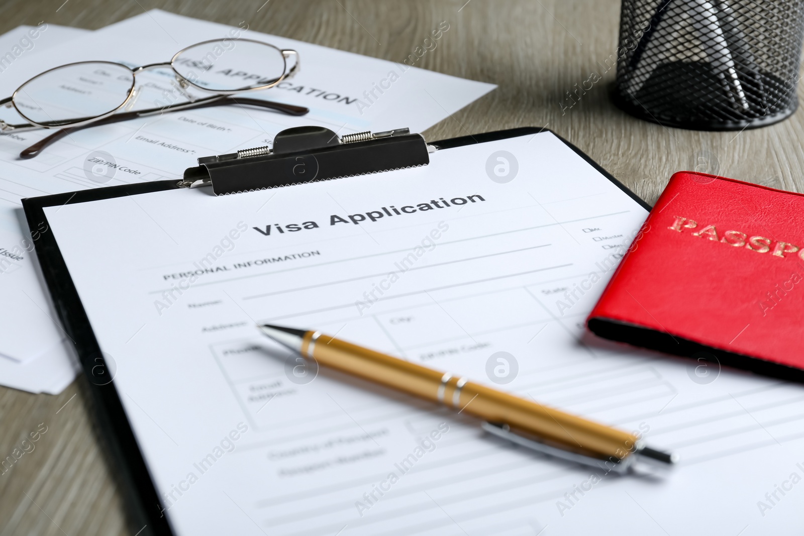 Photo of Visa application form for immigration, passport and pen on table, closeup