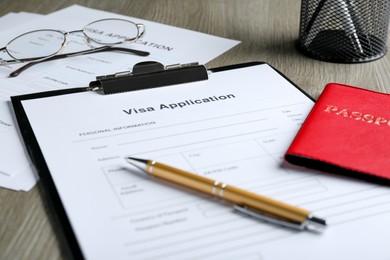 Photo of Visa application form for immigration, passport and pen on table, closeup