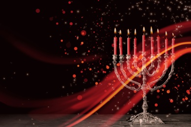 Silver menorah with burning candles on table against black background, space for text. Hanukkah celebration