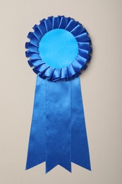 Photo of Blue award ribbon on beige background, top view